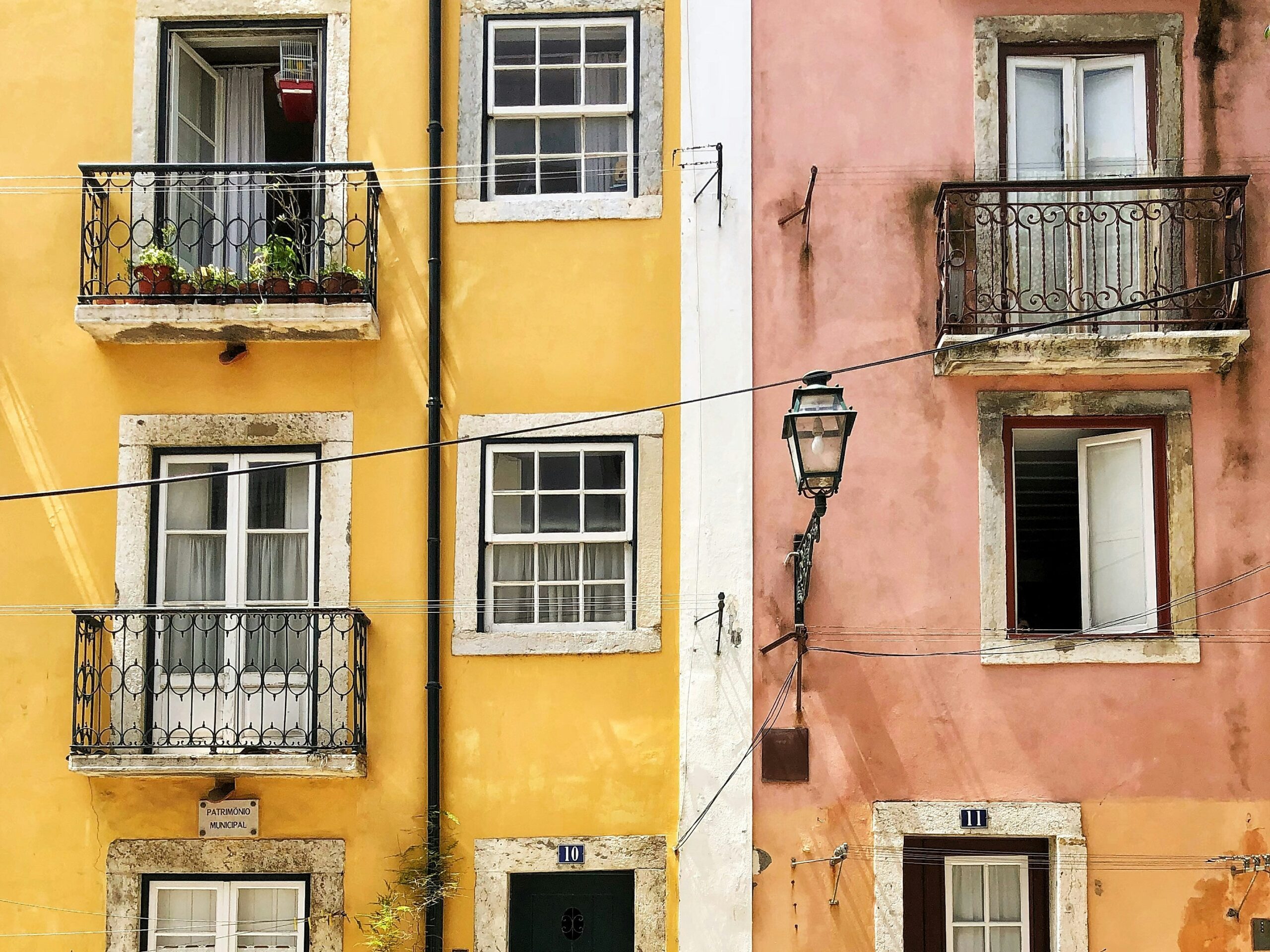 Vibrant pink and yellow suitcases against a backdrop of white buildings in Santorini