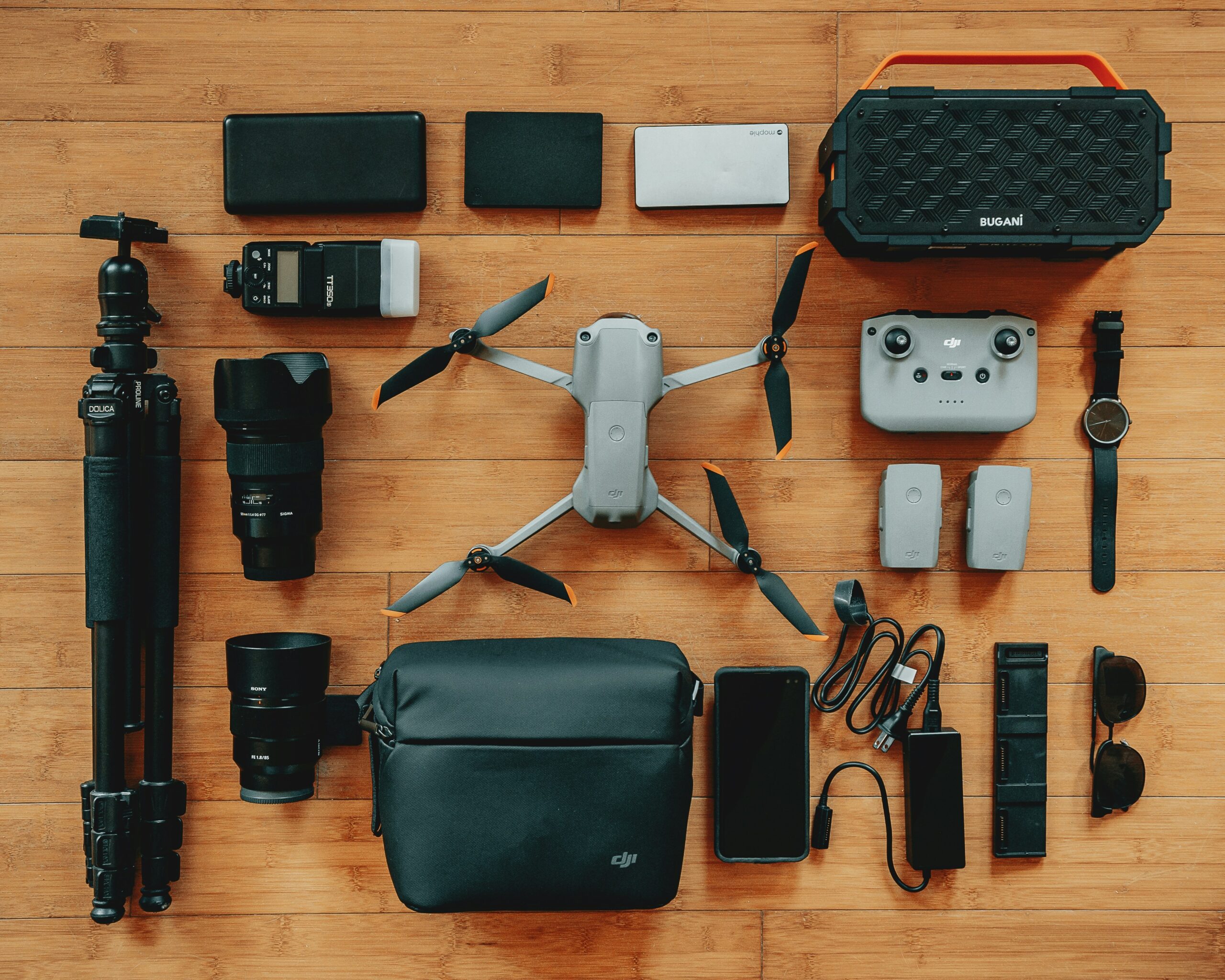 A selection of travel accessories including camera gear and chargers laid out neatly