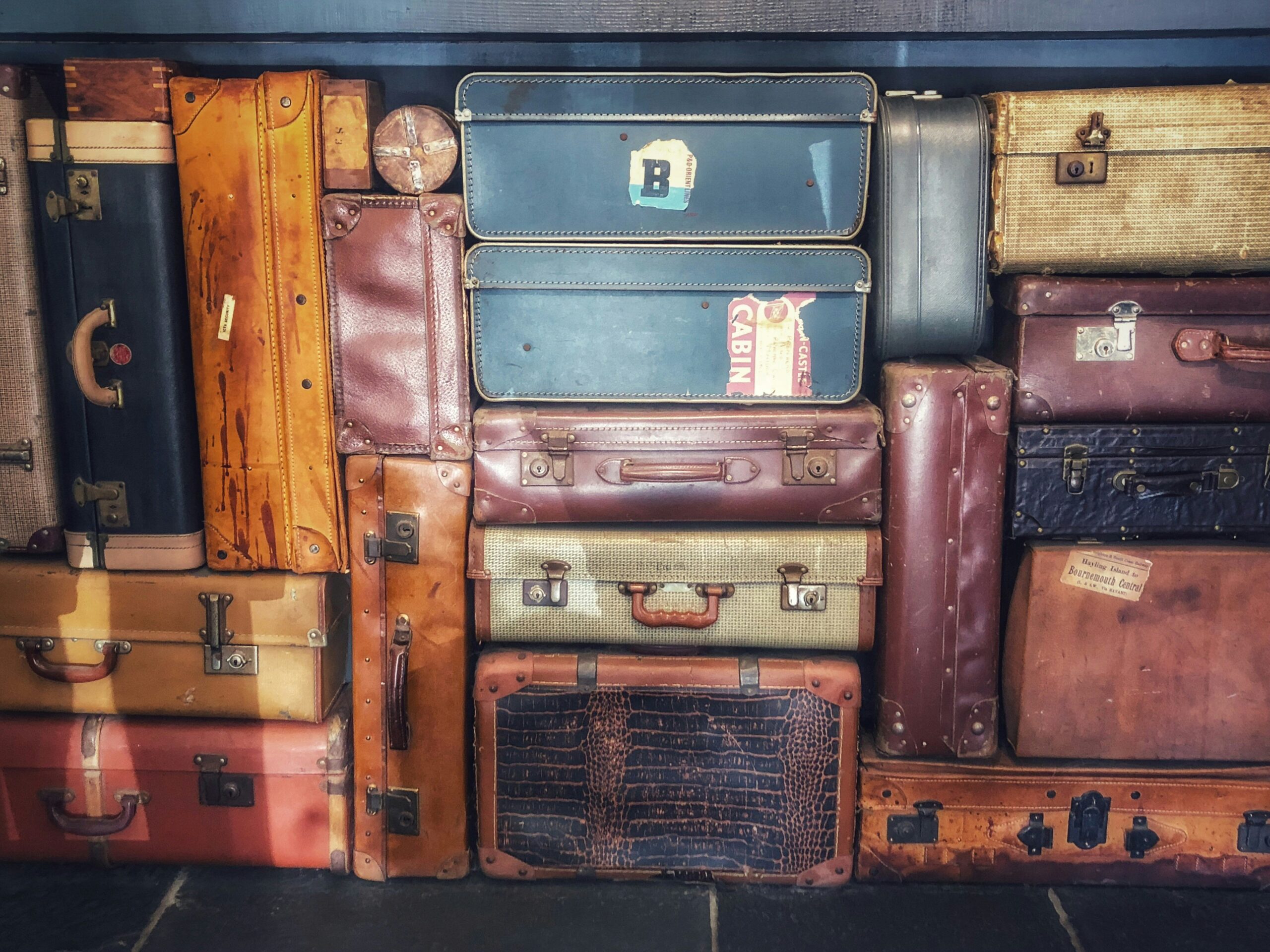 Row of brightly colored hard-shell suitcases in hues like neon pink, electric blue, and lime green lined up against a white background.