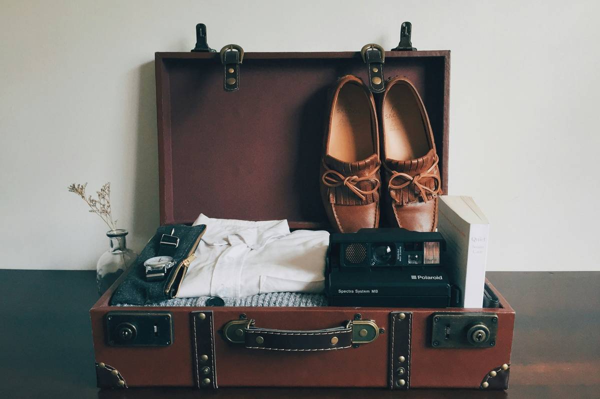 A vintage Tamagotchi toy sitting on top of a modern travel suitcase.