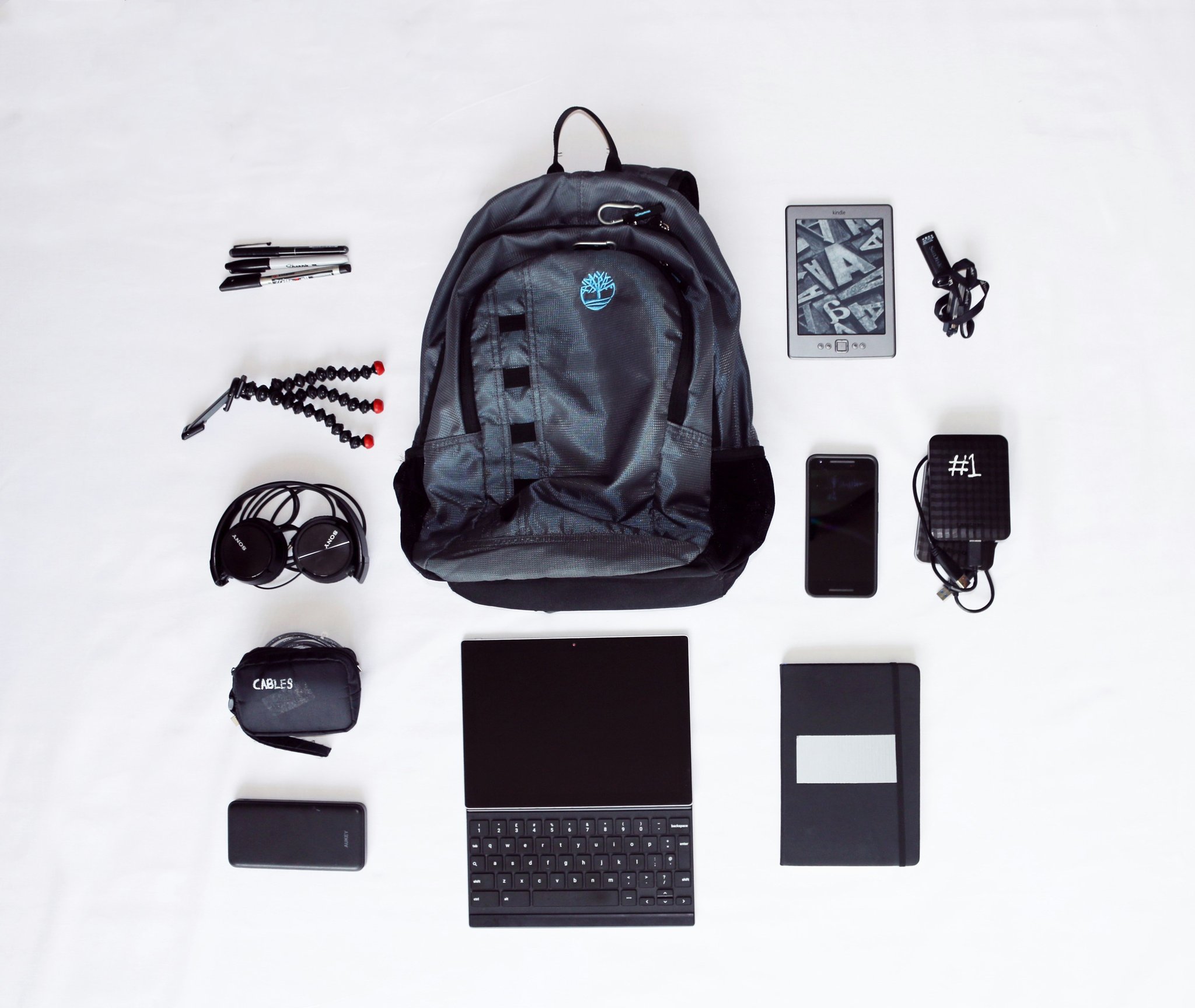 An influencer posing happily beside her well-packed suitcase containing organized gadgets