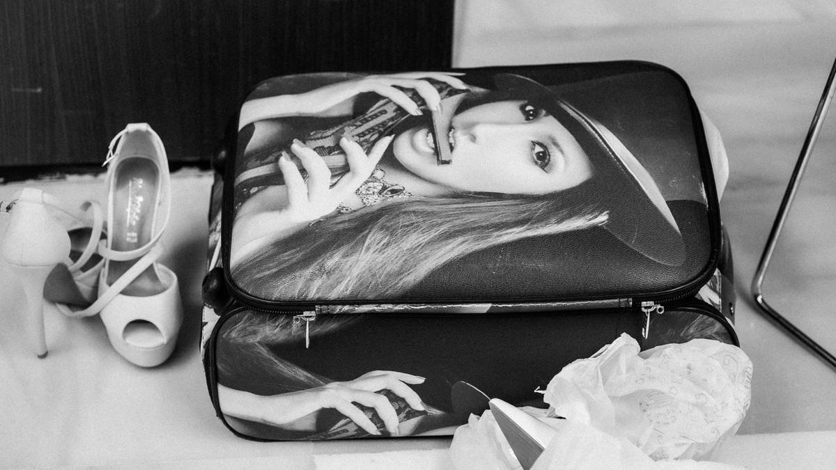 Shiny silver Rimowa suitcase paired with designer accessories on a marble floor.