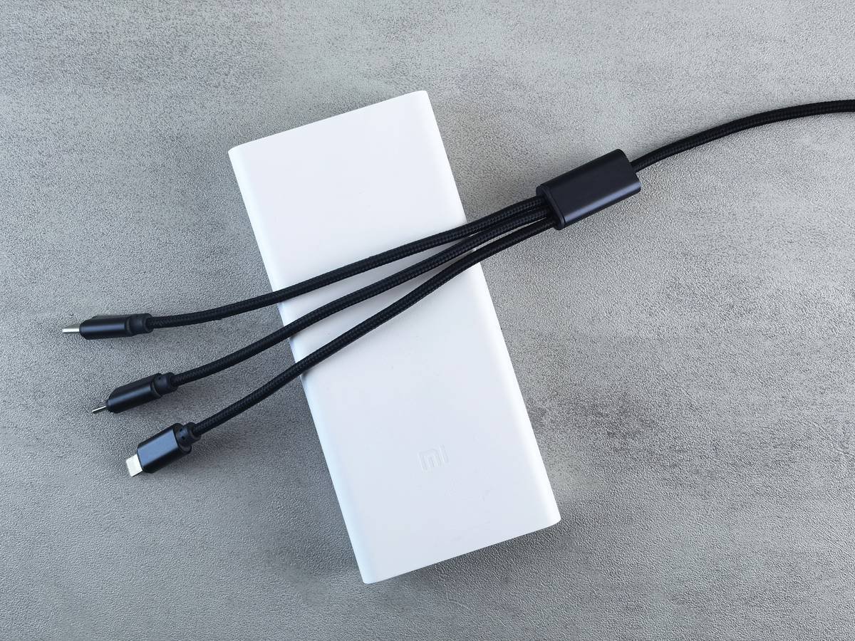 A sleek black power bank with USB-C ports sitting beside a DSLR camera