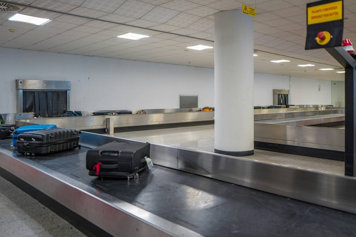 A stylish traveler posing next to colorful designer luggage at an airport